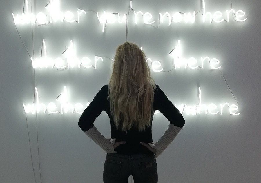 Curator Alexandra Kollaros in front of neon artwork